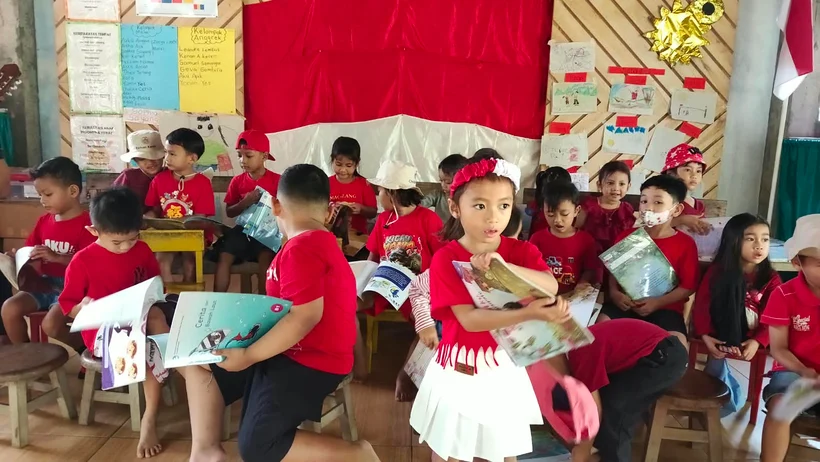 Joglo students each get a book to look at pictures and read information about Indonesia to discuss with their friends.