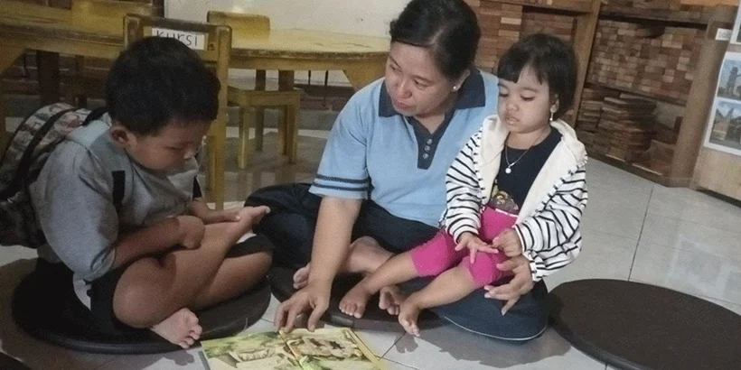 Ninok reading a book with Samuel and Kalea at Paud Joglo, photo taken on May 9, 2024 by Nadif