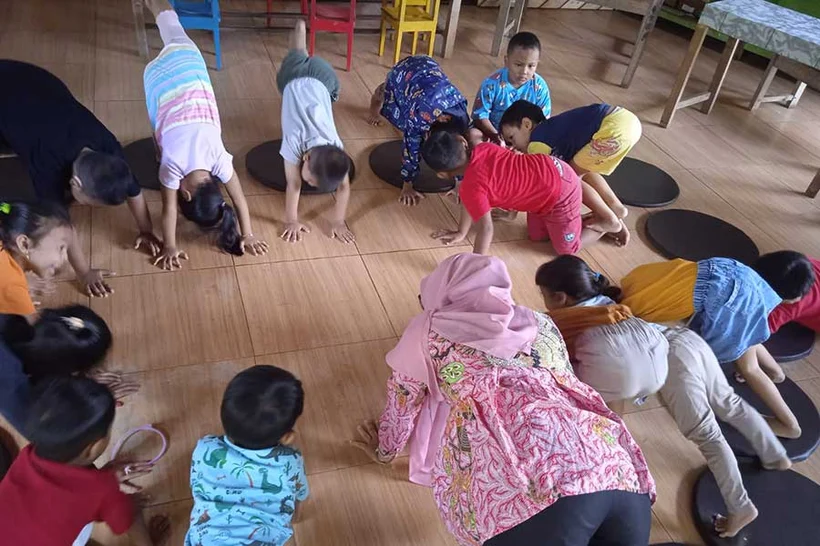 Children at Joglo Preschool participate in the Downward Dog activity.