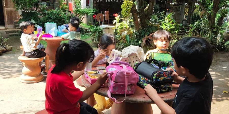 Children eat together outdoors.